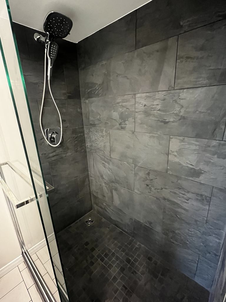 A walk-in shower with black tiles and two recessed niches for storage, designed with a modern aesthetic.